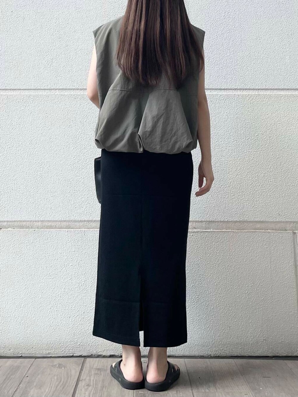 ブラック系のスカート、グリーン系のベストを着用したレディースの夏コーディネートの2枚目の写真