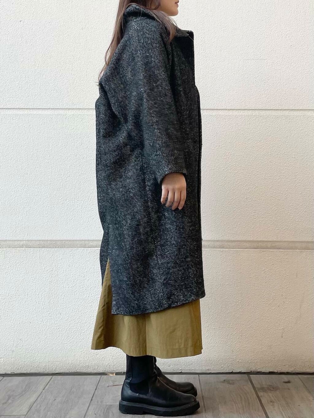 イエロー系のワンピース、ブラック系のその他アウターを着用したレディースの冬コーディネートの4枚目の写真