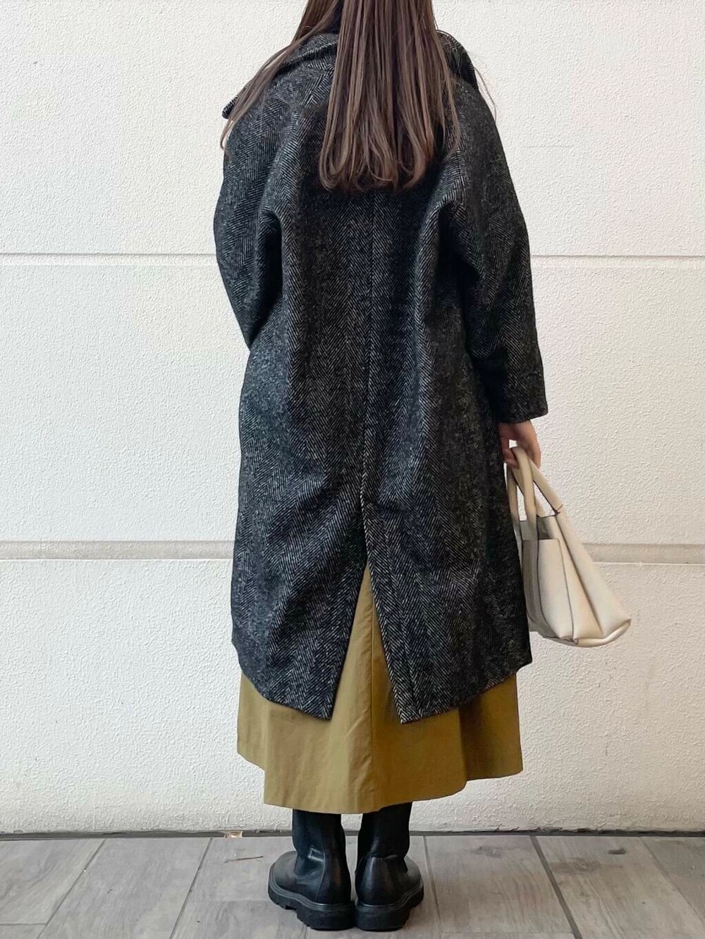 イエロー系のワンピース、ブラック系のその他アウターを着用したレディースの冬コーディネートの3枚目の写真