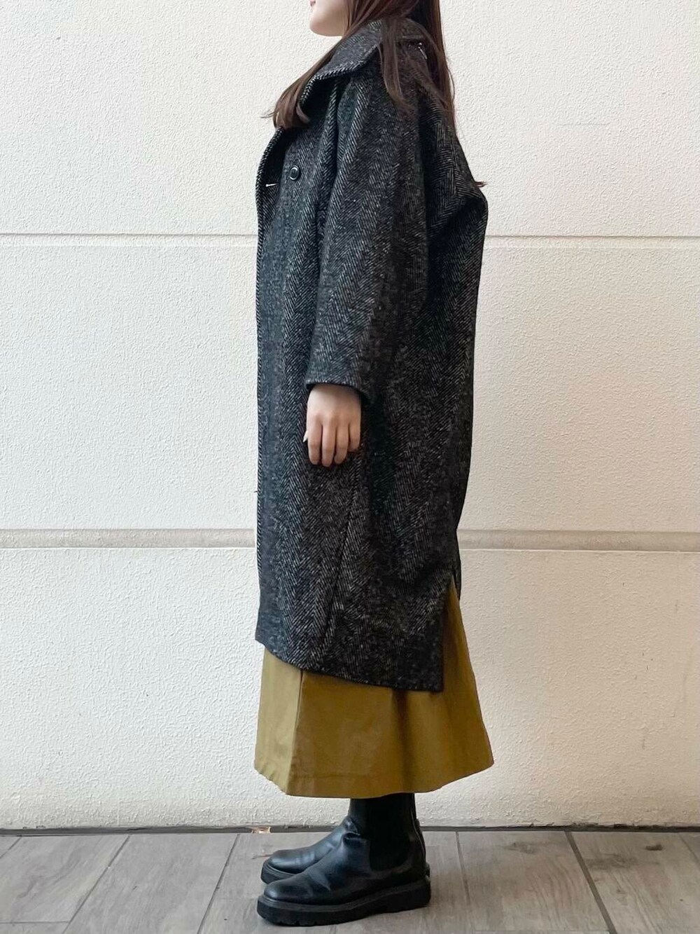 イエロー系のワンピース、ブラック系のその他アウターを着用したレディースの冬コーディネートの2枚目の写真