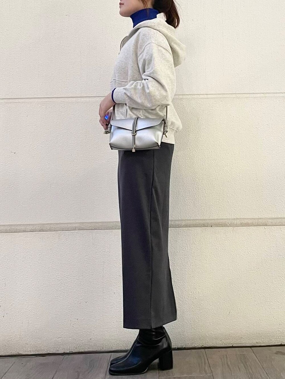 ブルー系のニット/セーター、ホワイト系のパーカー、グレー系のスカートを着用したレディースの冬コーディネートの2枚目の写真