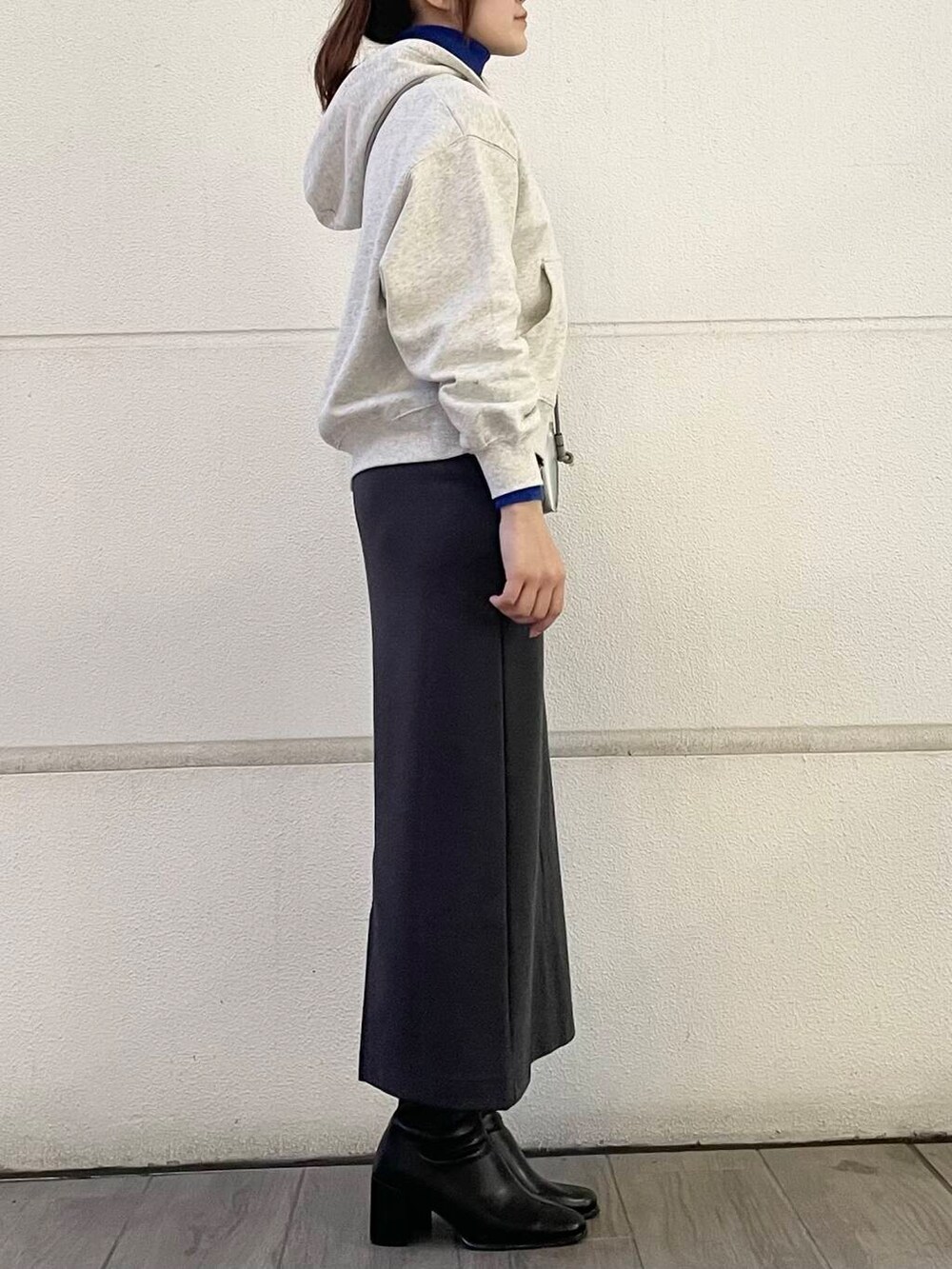 ブルー系のニット/セーター、ホワイト系のパーカー、グレー系のスカートを着用したレディースの冬コーディネートの4枚目の写真