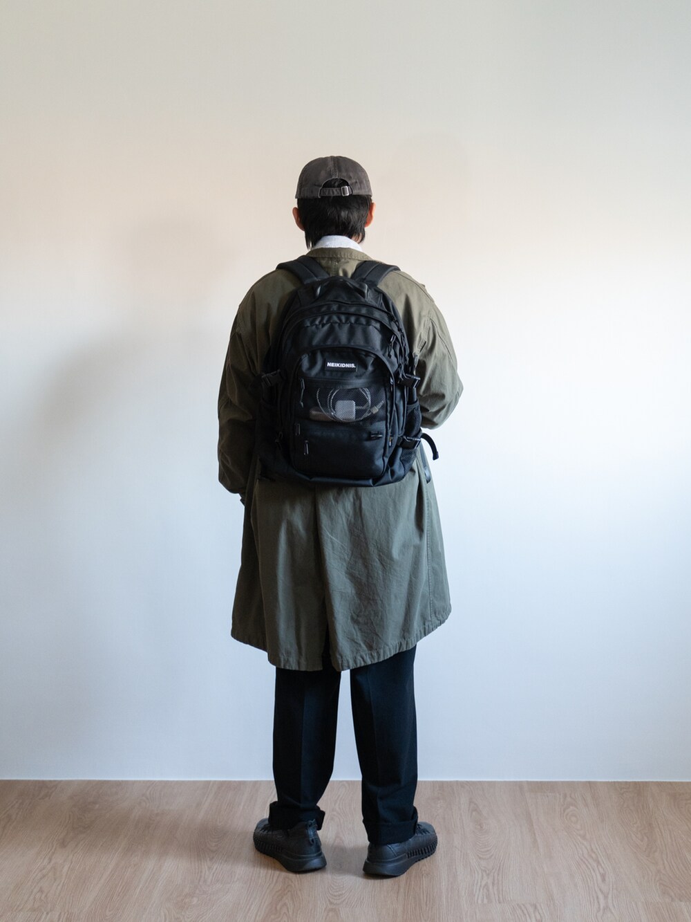 ブラック系のバックパック/リュック、グリーン系のミリタリージャケット、ブラック系のチノパンツを着用したメンズの冬コーディネートの2枚目の写真