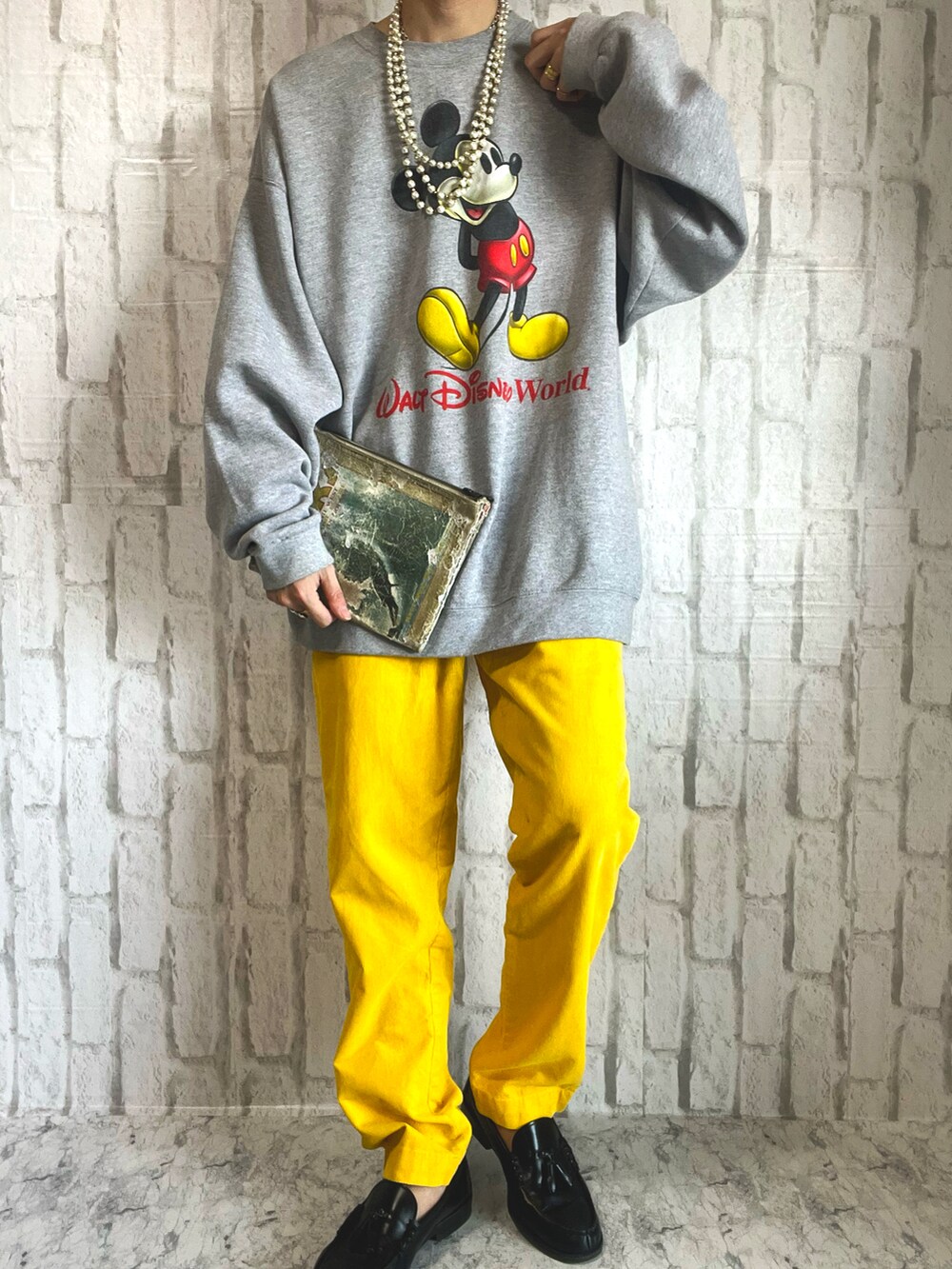 グレー系のスウェット、ベージュ系のクラッチバッグ、イエロー系のパンツを着用したメンズの春コーディネートの2枚目の写真