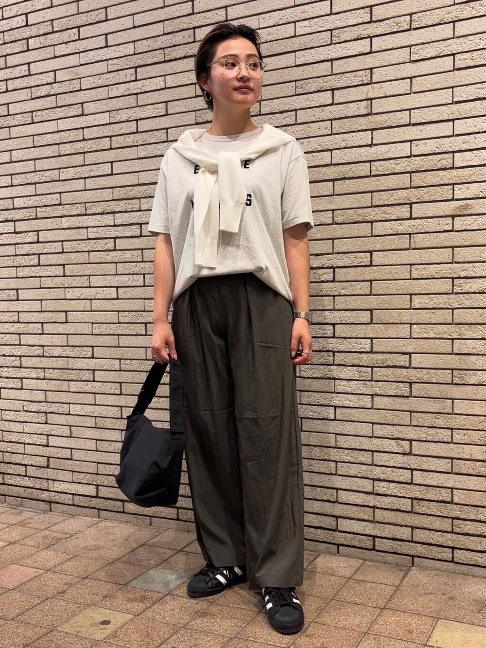 ブラック系のショルダーバッグ、グレー系のTシャツ/カットソー、ホワイト系のカーディガン/ボレロを着用したレディースの夏コーディネートの2枚目の写真