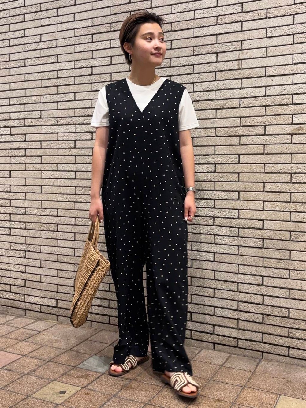 ベージュ系のトートバッグ、ブラック系のサロペット/オーバーオール、ブラウン系のサンダルを着用したレディースの夏コーディネートの2枚目の写真