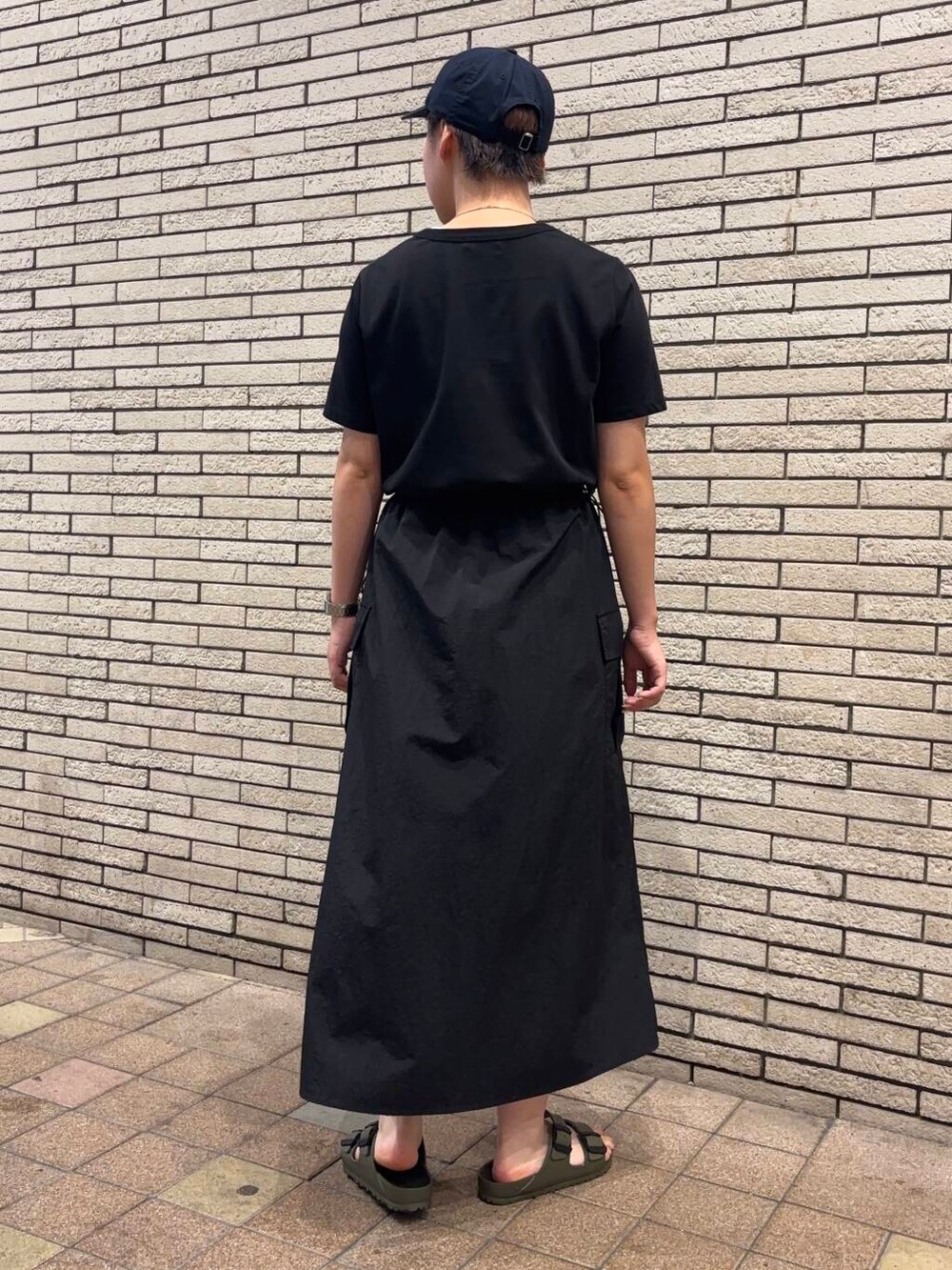 ブラック系のワンピース、グリーン系のサンダル、ブルー系のキャップを着用したレディースの夏コーディネートの4枚目の写真