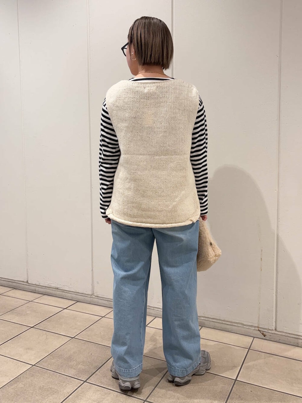 ホワイト系のニット/セーター、ベージュ系のハンドバッグ、ブラック系のTシャツ/カットソーを着用したレディースの冬コーディネートの3枚目の写真