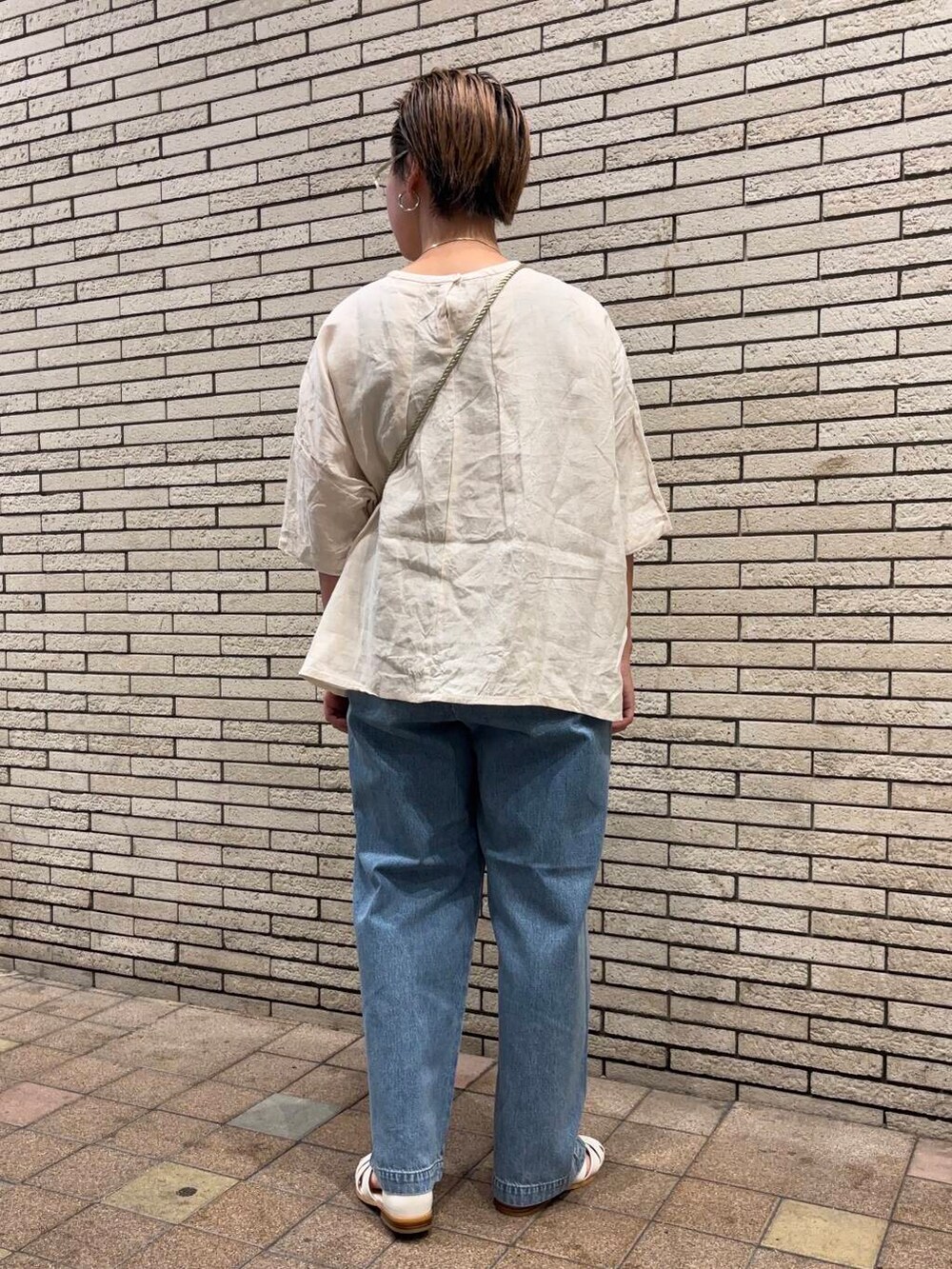 ブルー系のデニムパンツ、ホワイト系のサンダル、ホワイト系のショルダーバッグを着用したレディースの夏コーディネートの4枚目の写真