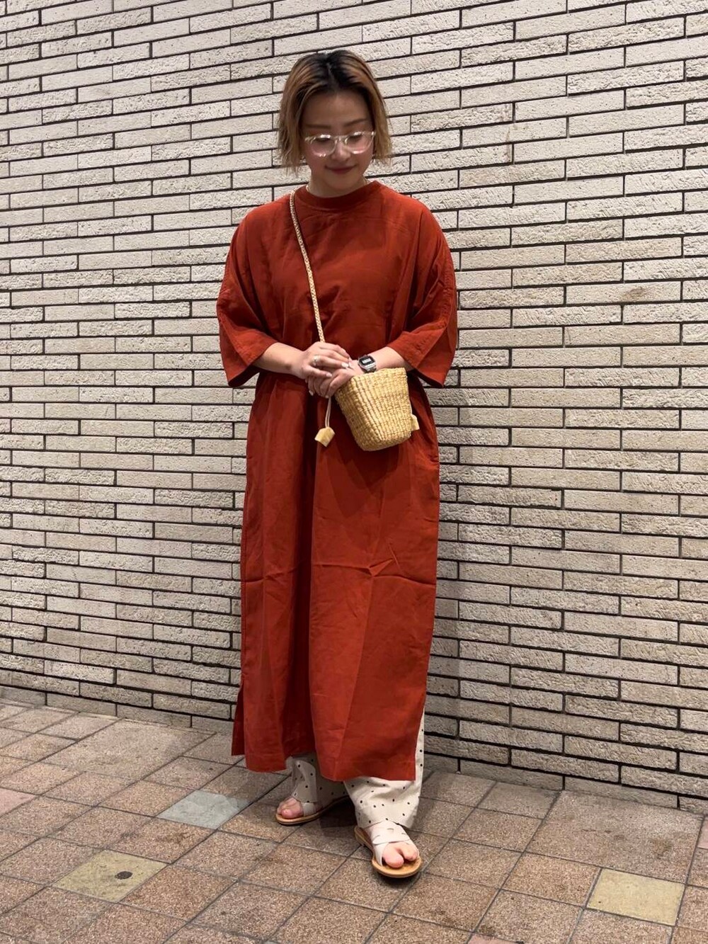 ブラック系のハンドバッグ、オレンジ系のワンピース、ホワイト系のサンダルを着用したレディースの春コーディネートの2枚目の写真