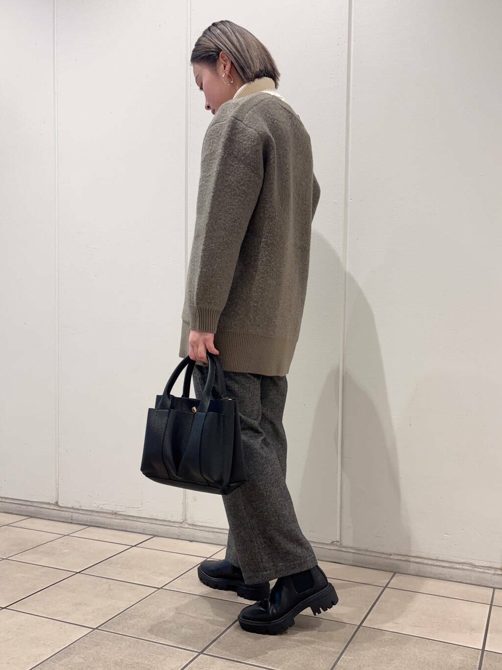 ブラック系のブーツ、ブラウン系のカーディガン/ボレロ、グレー系のその他パンツを着用したレディースの冬コーディネートの2枚目の写真