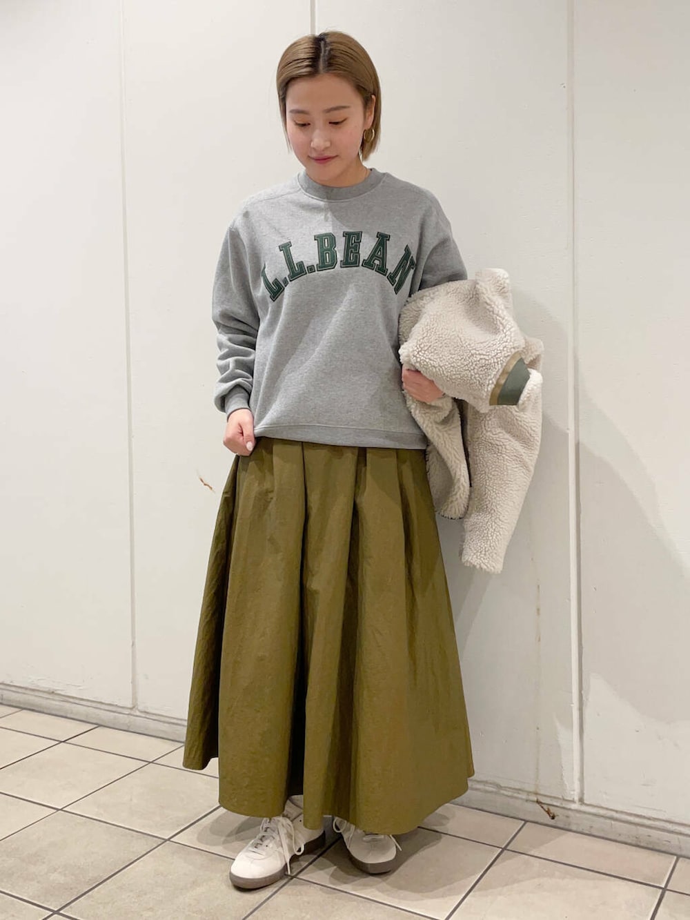 ホワイト系のスニーカー、グリーン系のスカート、グレー系のスウェットを着用したレディースの秋コーディネートの4枚目の写真