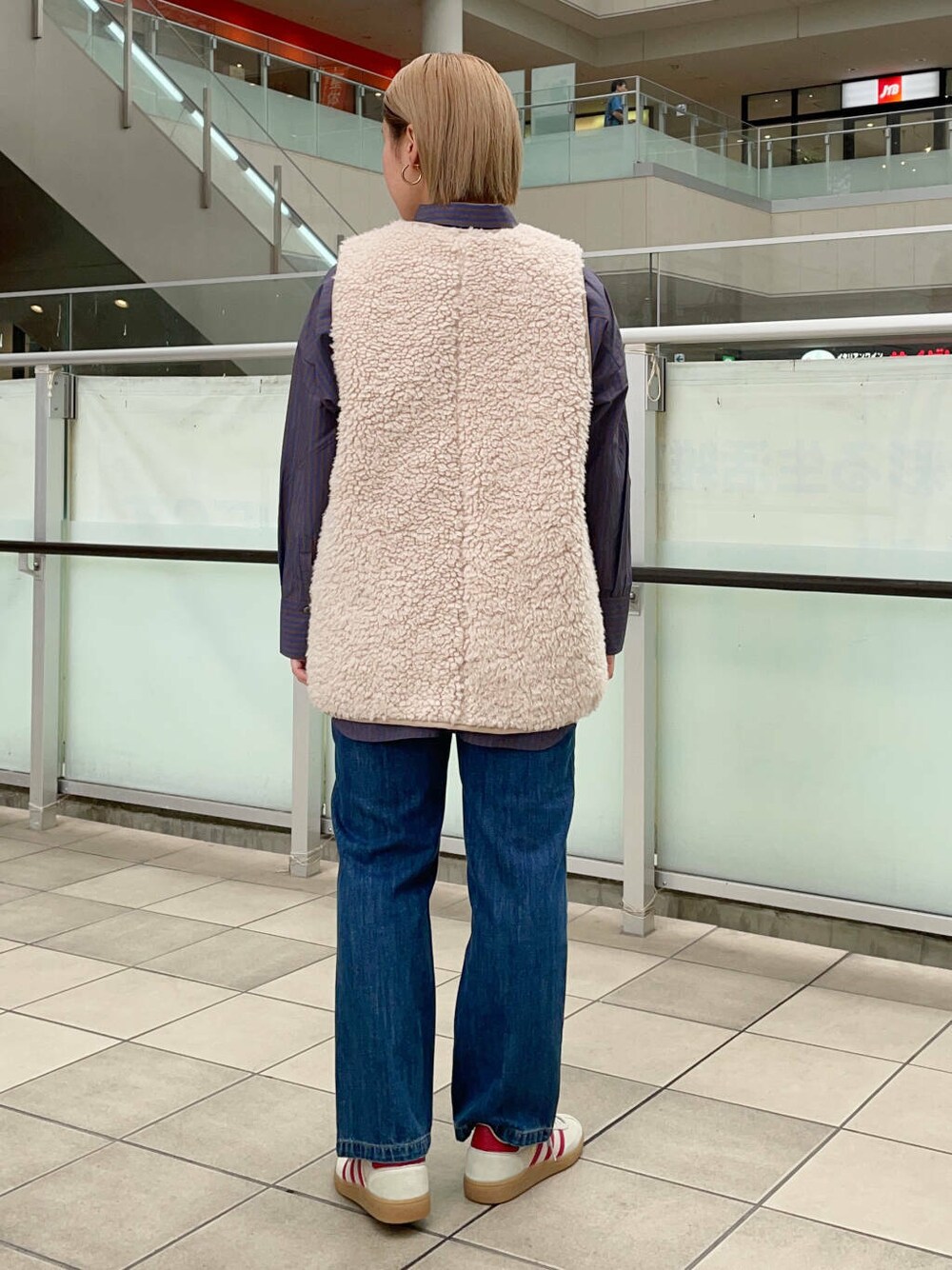 ブルー系のデニムパンツ、ベージュ系のベスト、ブルー系のシャツ/ブラウスを着用したレディースの秋コーディネートの4枚目の写真