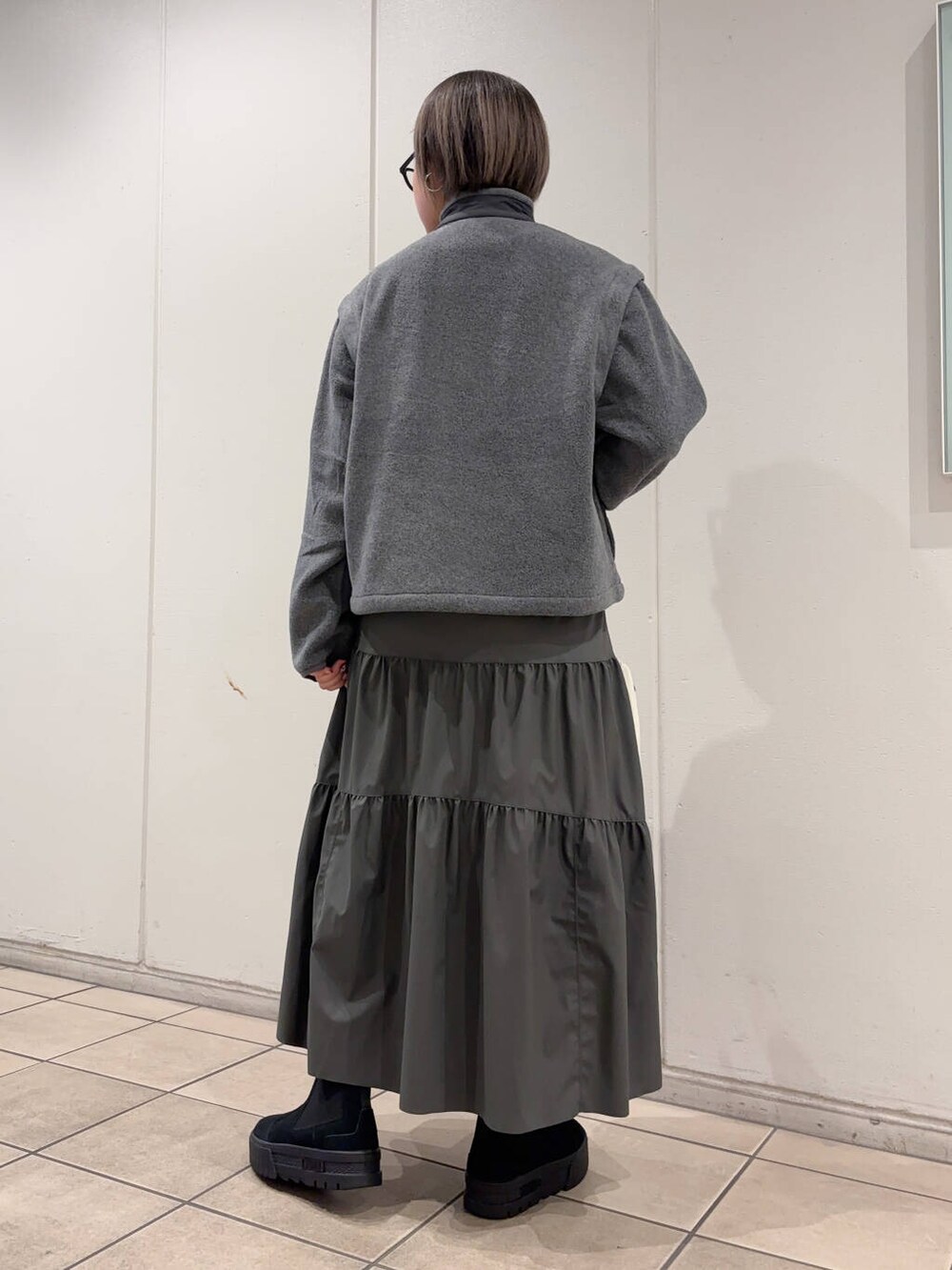 ブラック系のブーツ、グレー系のブルゾン、グレー系のスカートを着用したレディースの冬コーディネートの3枚目の写真