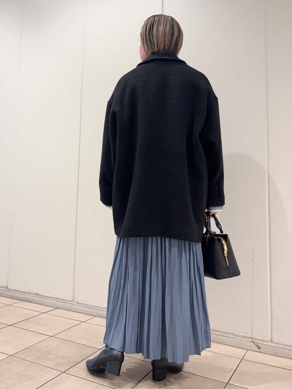 ブラック系のブーツ、ブラック系のその他アウター、ブルー系のスカートを着用したレディースの冬コーディネートの3枚目の写真