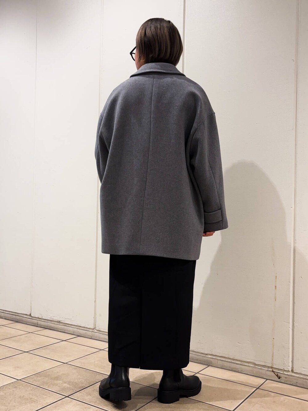 グレー系のその他アウター、ブラック系のブーツ、ホワイト系のニット/セーターを着用したレディースの冬コーディネートの5枚目の写真