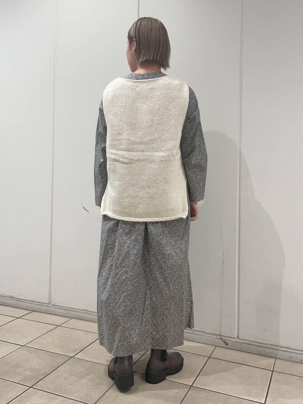 ホワイト系のニット/セーター、ブラウン系のブーツ、グレー系のワンピースを着用したレディースの秋コーディネートの4枚目の写真