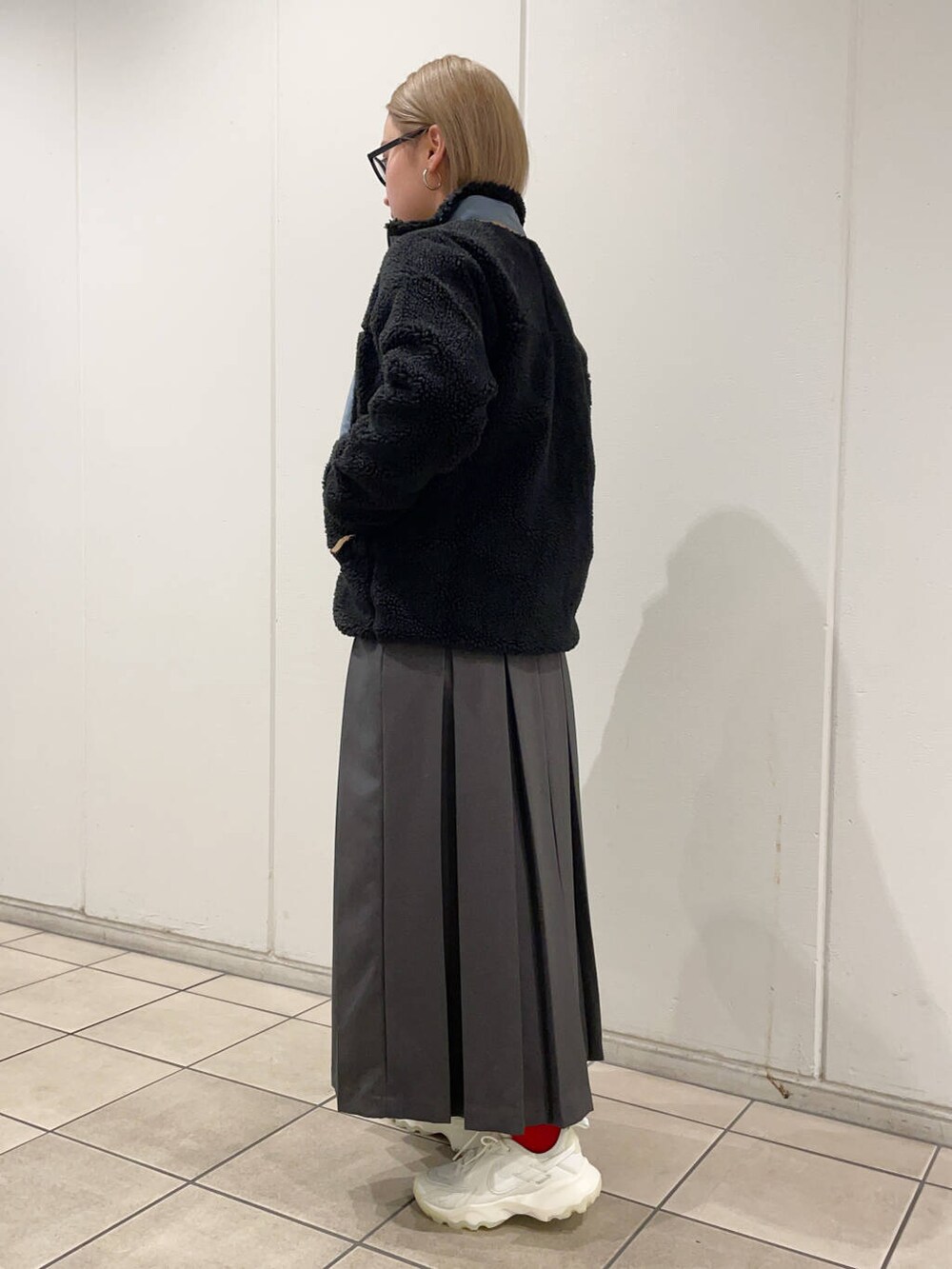 グレー系のスカート、グレー系のスウェット、ブラック系のテーラードジャケットを着用したレディースの秋コーディネートの2枚目の写真