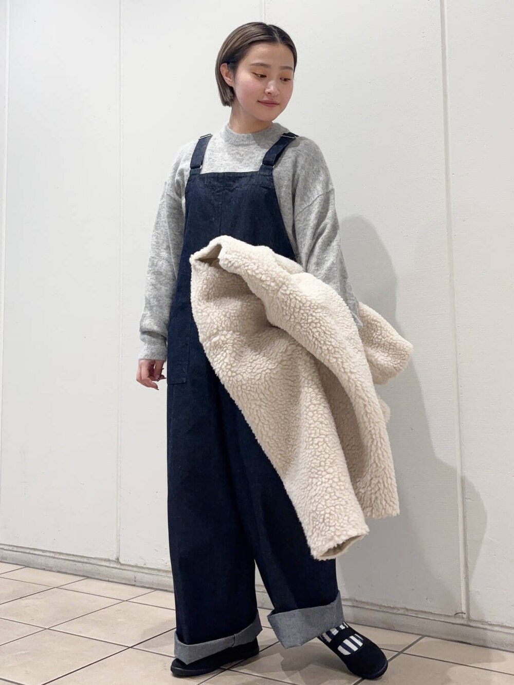 ブラック系のスニーカー、ホワイト系のその他アウター、ブルー系のサロペット/オーバーオールを着用したレディースの冬コーディネートの2枚目の写真