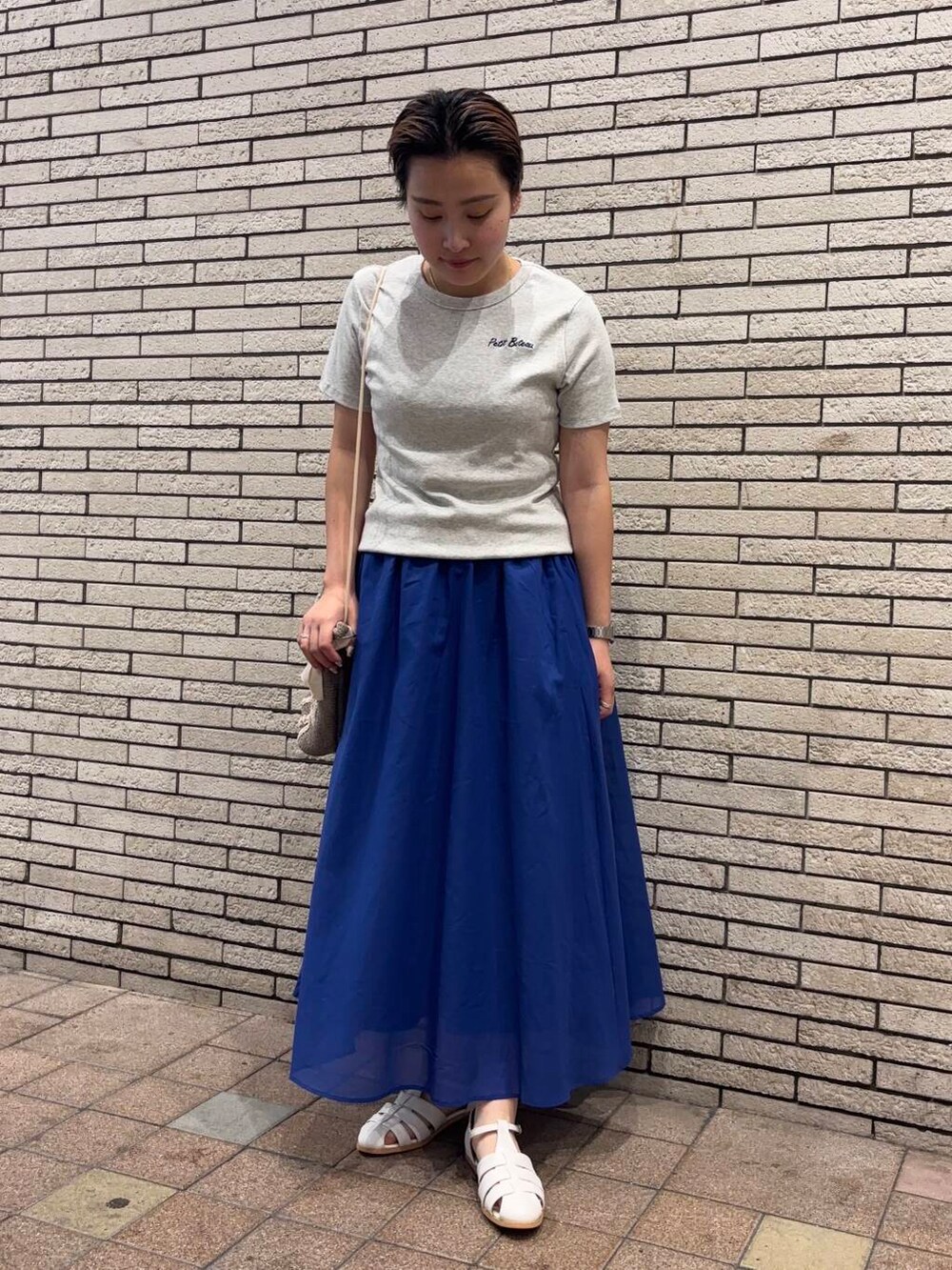 ホワイト系のサンダル、グレー系のショルダーバッグ、ブルー系のスカートを着用したレディースの夏コーディネートの2枚目の写真