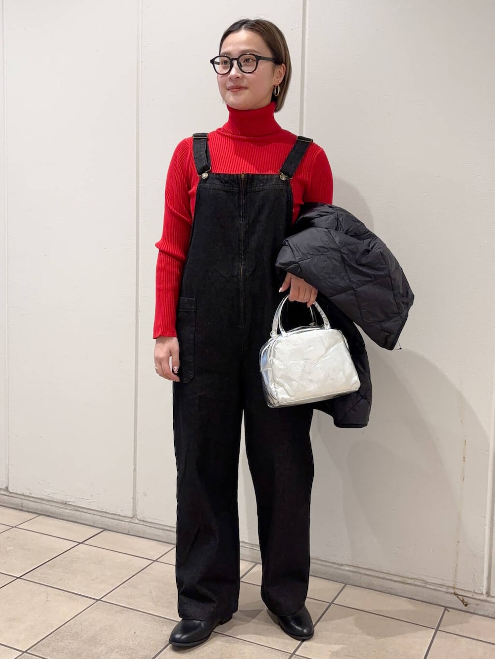 ブラック系のダウンジャケット/コート、ブラック系のサロペット/オーバーオール、ブラック系のブーツを着用したレディースの冬コーディネートの2枚目の写真