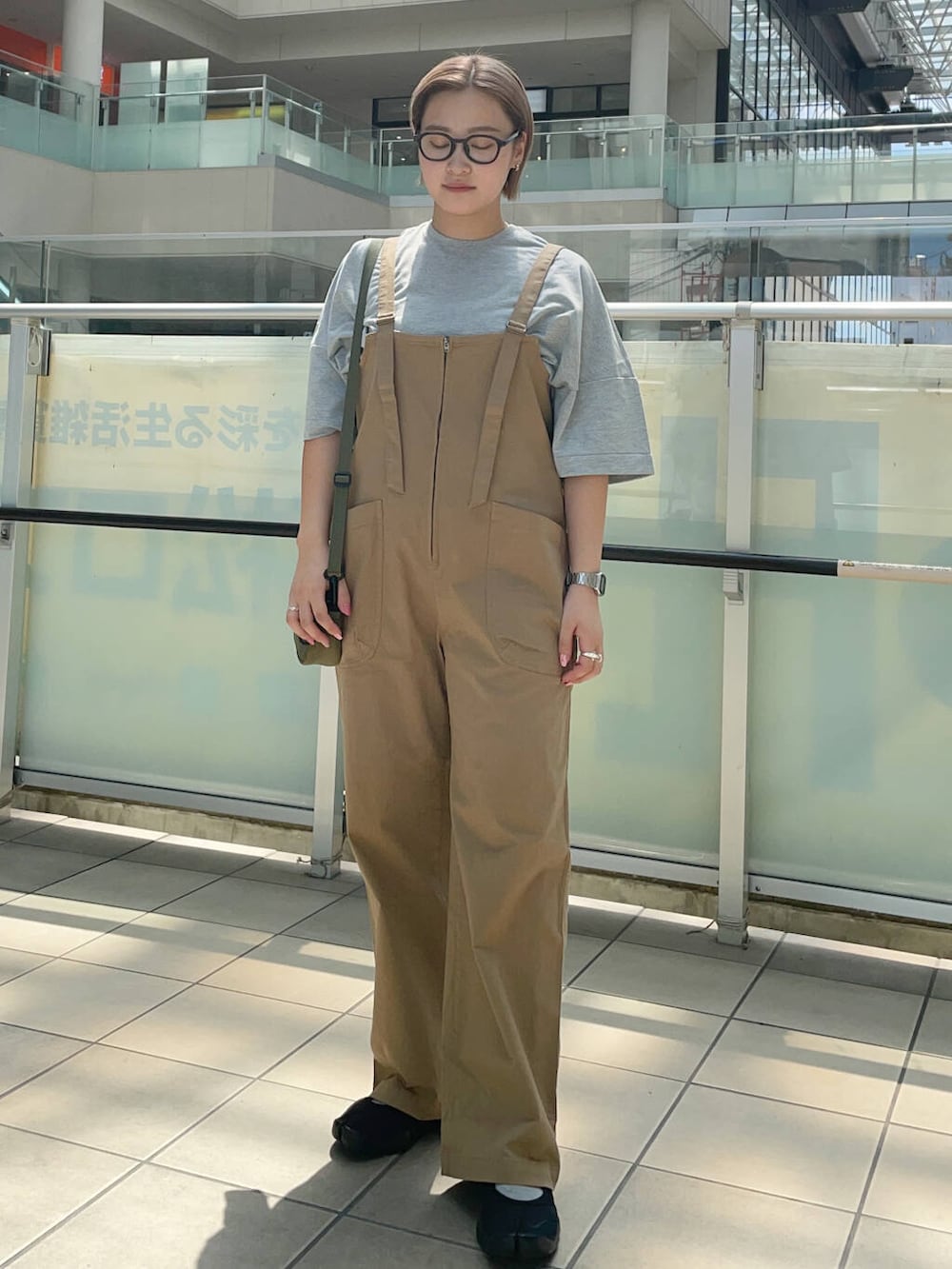 グリーン系のショルダーバッグ、イエロー系のサロペット/オーバーオール、グレー系のTシャツ/カットソーを着用したレディースの夏コーディネートの2枚目の写真