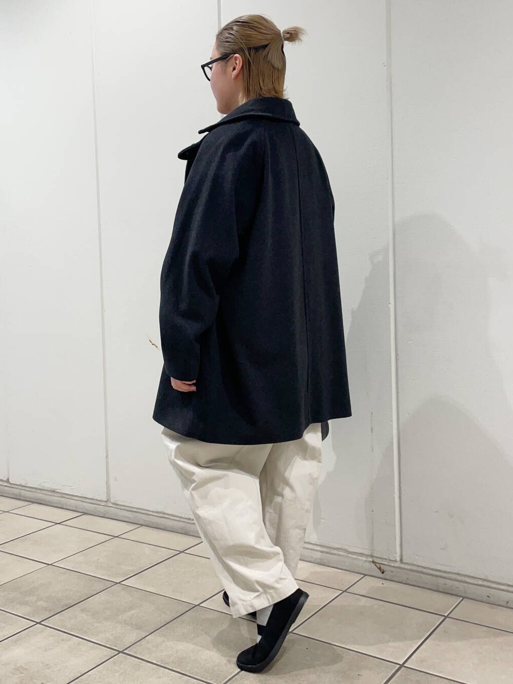 ブラック系のスニーカー、グレー系のピーコート、ホワイト系のその他パンツを着用したレディースの冬コーディネートの5枚目の写真