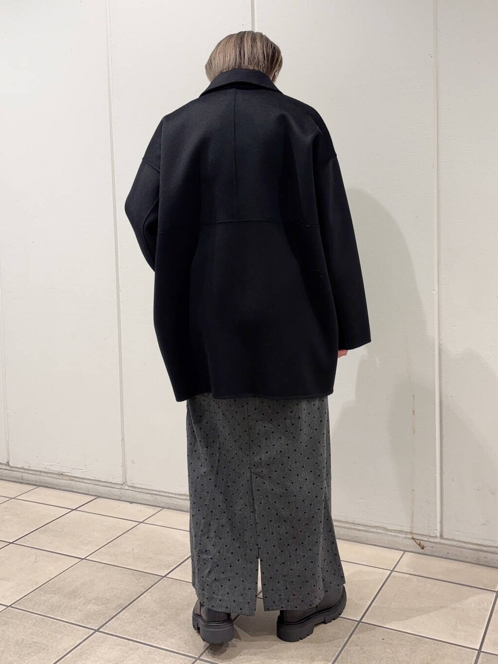 ブラック系のブーツ、ブラック系のステンカラーコート、ブラック系のニット/セーターを着用したレディースの冬コーディネートの3枚目の写真