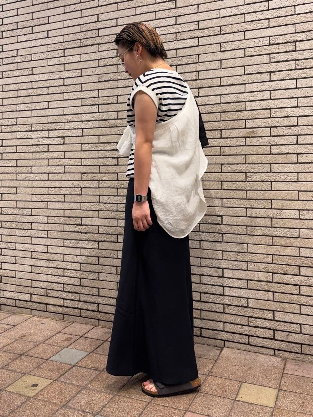 ブラック系のショルダーバッグ、グレー系のサンダル、ホワイト系のTシャツ/カットソーを着用したレディースの夏コーディネートの2枚目の写真