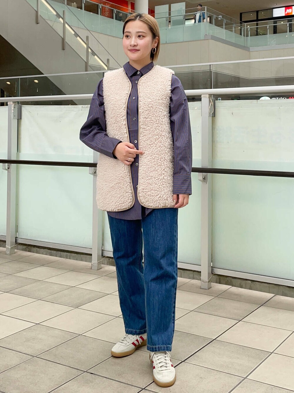 ブルー系のデニムパンツ、ベージュ系のベスト、ブルー系のシャツ/ブラウスを着用したレディースの秋コーディネートの2枚目の写真