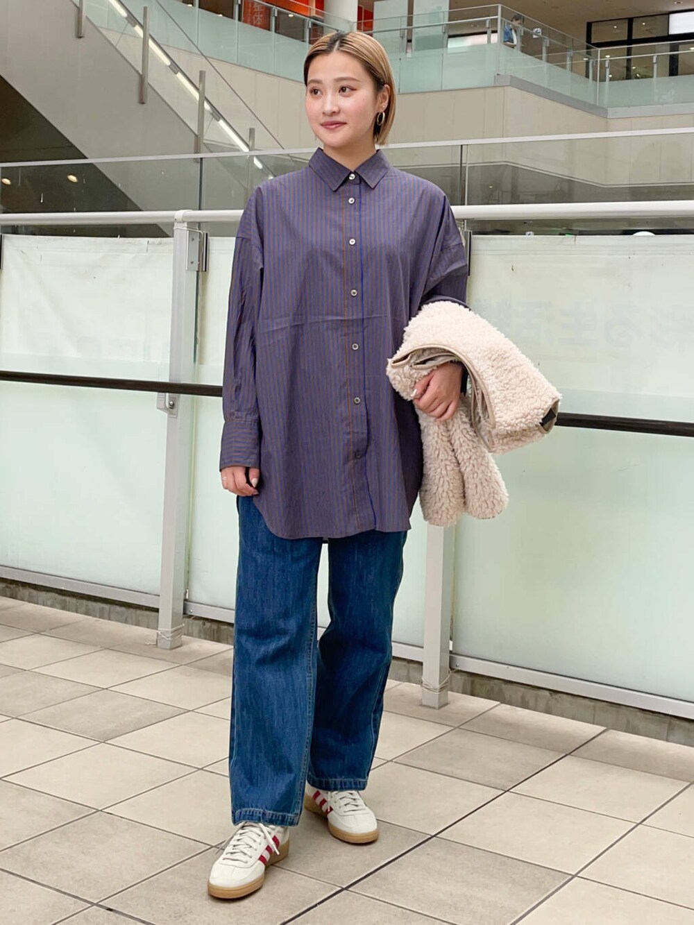 ブルー系のデニムパンツ、ベージュ系のベスト、ブルー系のシャツ/ブラウスを着用したレディースの秋コーディネートの5枚目の写真