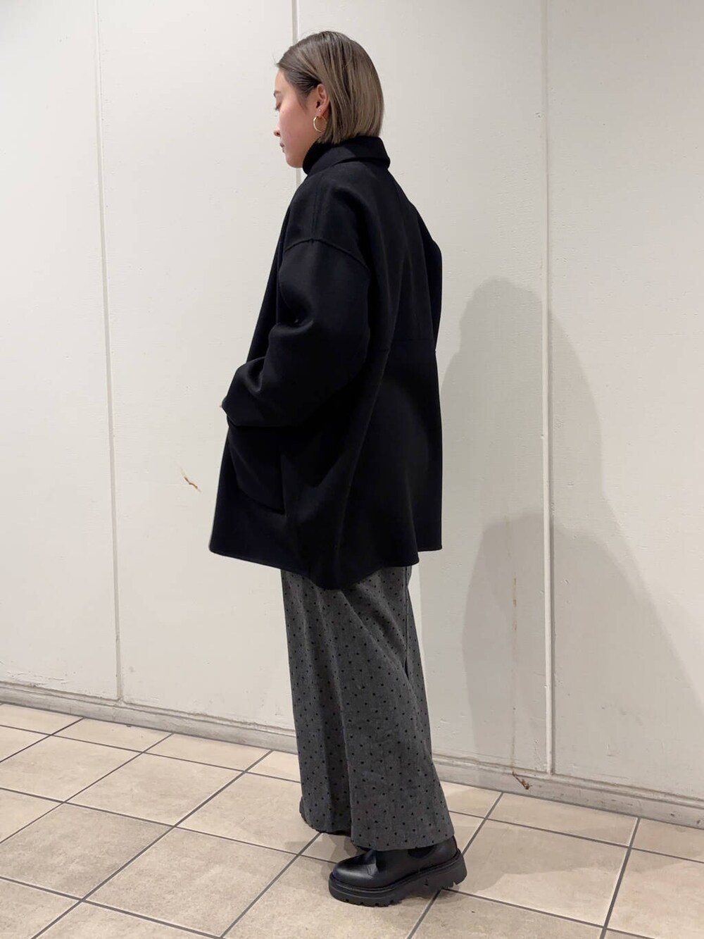 ブラック系のブーツ、ブラック系のステンカラーコート、ブラック系のニット/セーターを着用したレディースの冬コーディネートの2枚目の写真