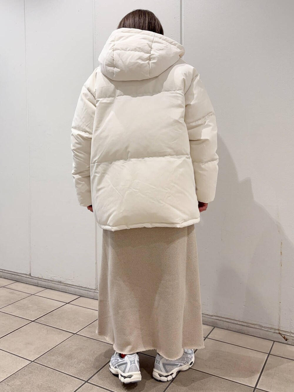 ベージュ系のTシャツ/カットソー、ベージュ系のスカート、ホワイト系のダウンジャケット/コートを着用したレディースの冬コーディネートの4枚目の写真