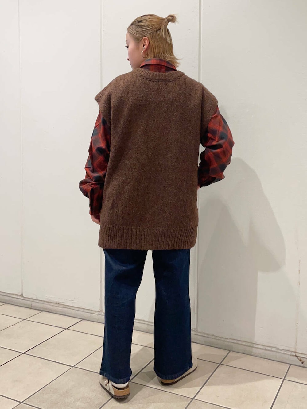 レッド系のシャツ/ブラウス、ブルー系のデニムパンツ、ブラウン系のベストを着用したレディースの秋コーディネートの4枚目の写真