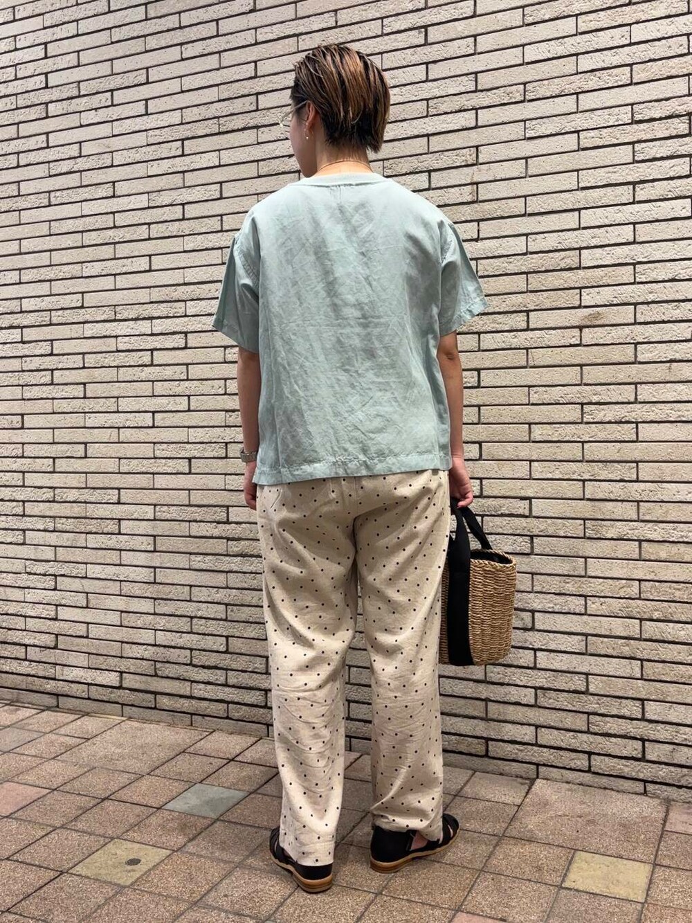 ベージュ系のハンドバッグ、ブラック系のサンダル、グリーン系のTシャツ/カットソーを着用したレディースの夏コーディネートの3枚目の写真