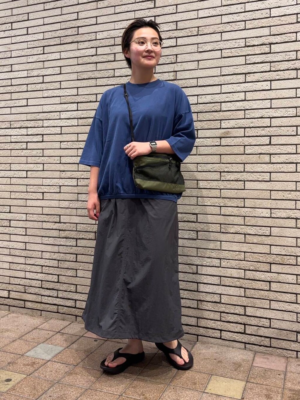 ブラック系のサンダル、グリーン系のショルダーバッグ、グレー系のスカートを着用したレディースの夏コーディネートの2枚目の写真