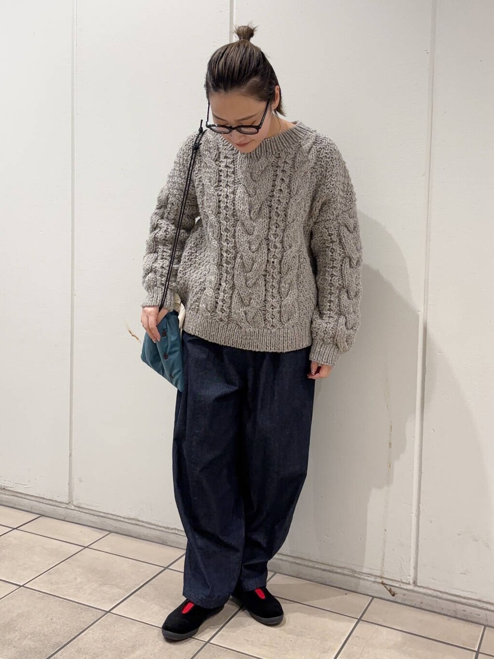 グレー系のニット/セーター、ブルー系のショルダーバッグ、ブルー系のデニムパンツを着用したレディースの冬コーディネートの2枚目の写真