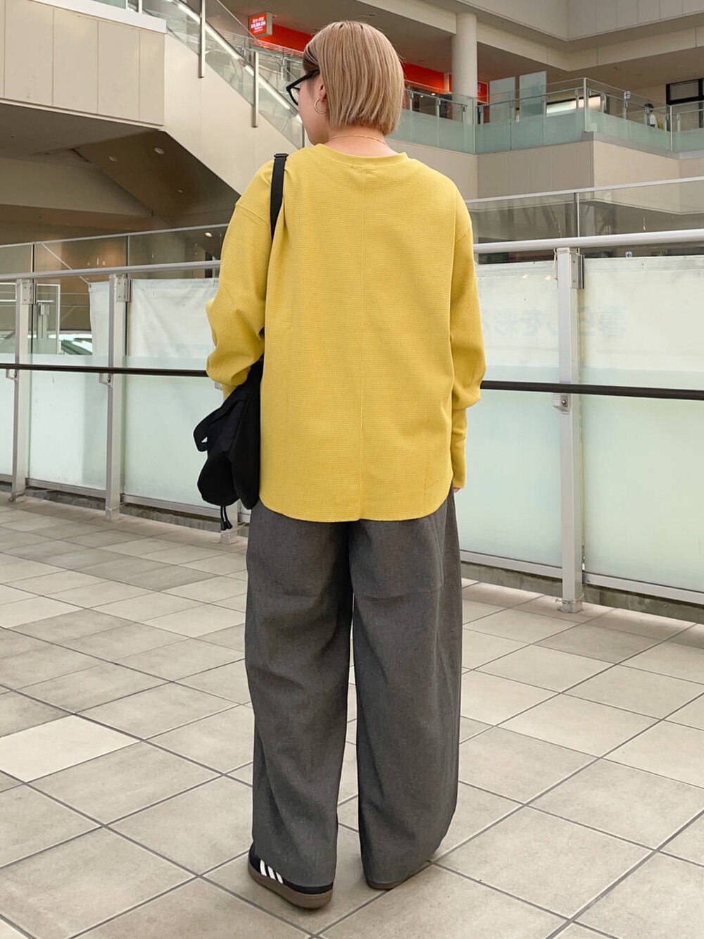 ブラック系のショルダーバッグ、ブラック系のスニーカー、イエロー系のTシャツ/カットソーを着用したレディースの秋コーディネートの5枚目の写真