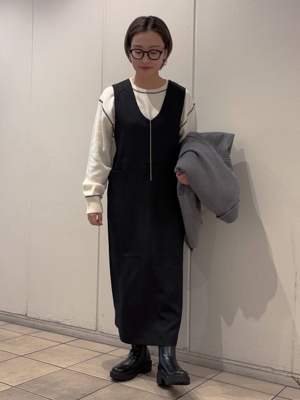 グレー系のその他アウター、ブラック系のブーツ、ホワイト系のニット/セーターを着用したレディースの冬コーディネートの2枚目の写真