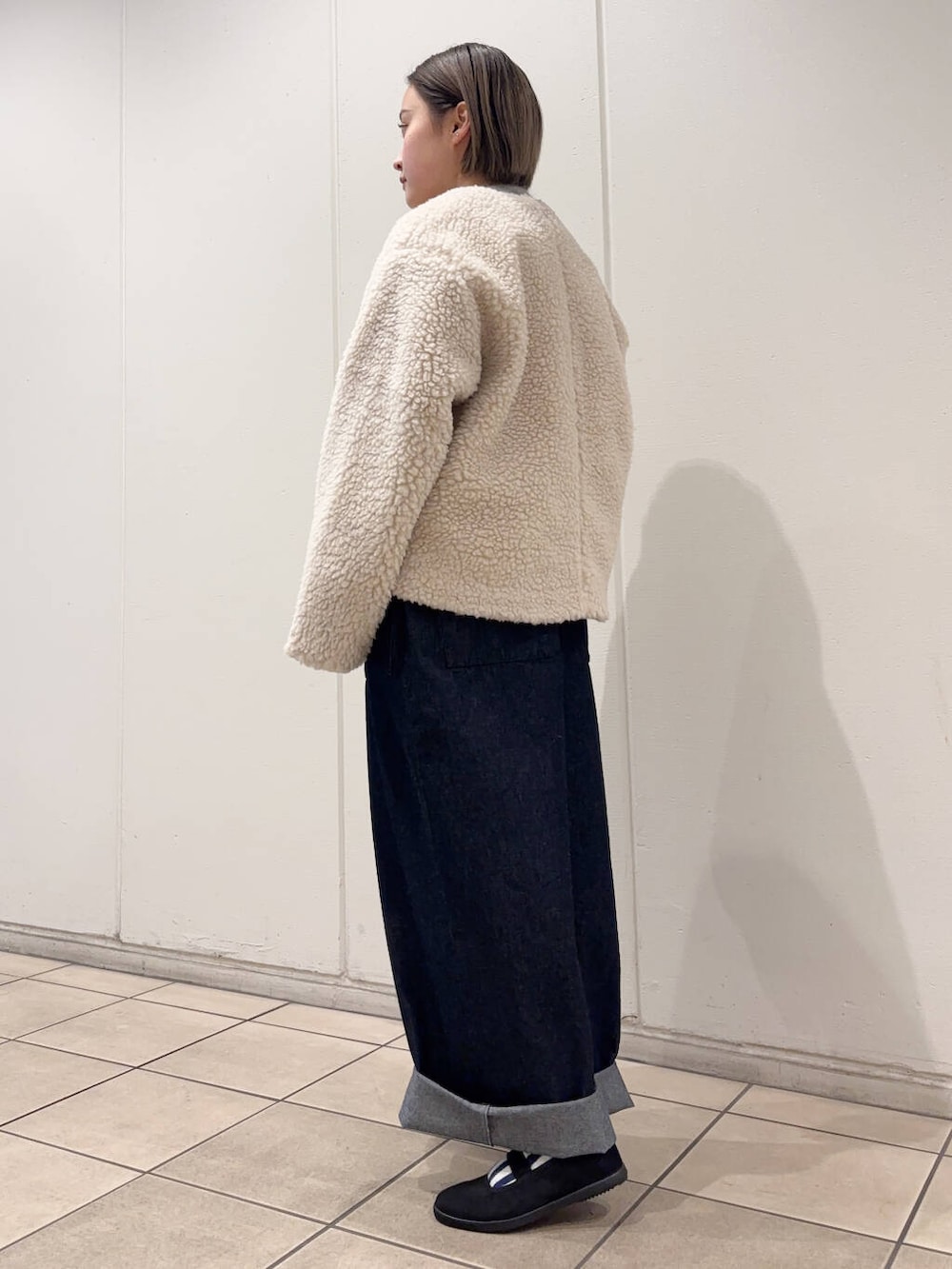 ブラック系のスニーカー、ホワイト系のその他アウター、ブルー系のサロペット/オーバーオールを着用したレディースの冬コーディネートの3枚目の写真