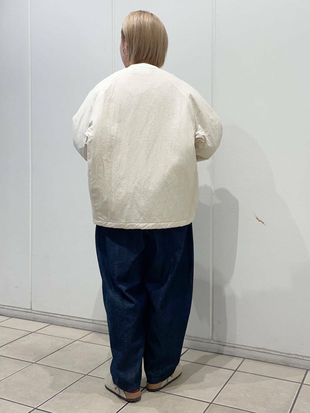 ブルー系のデニムパンツ、ブラウン系のハンドバッグ、ホワイト系のニット/セーターを着用したレディースの秋コーディネートの3枚目の写真