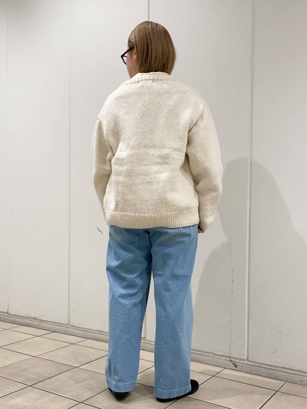 ブラック系のスニーカー、ホワイト系のニット/セーター、ブルー系のデニムパンツを着用したレディースの冬コーディネートの4枚目の写真