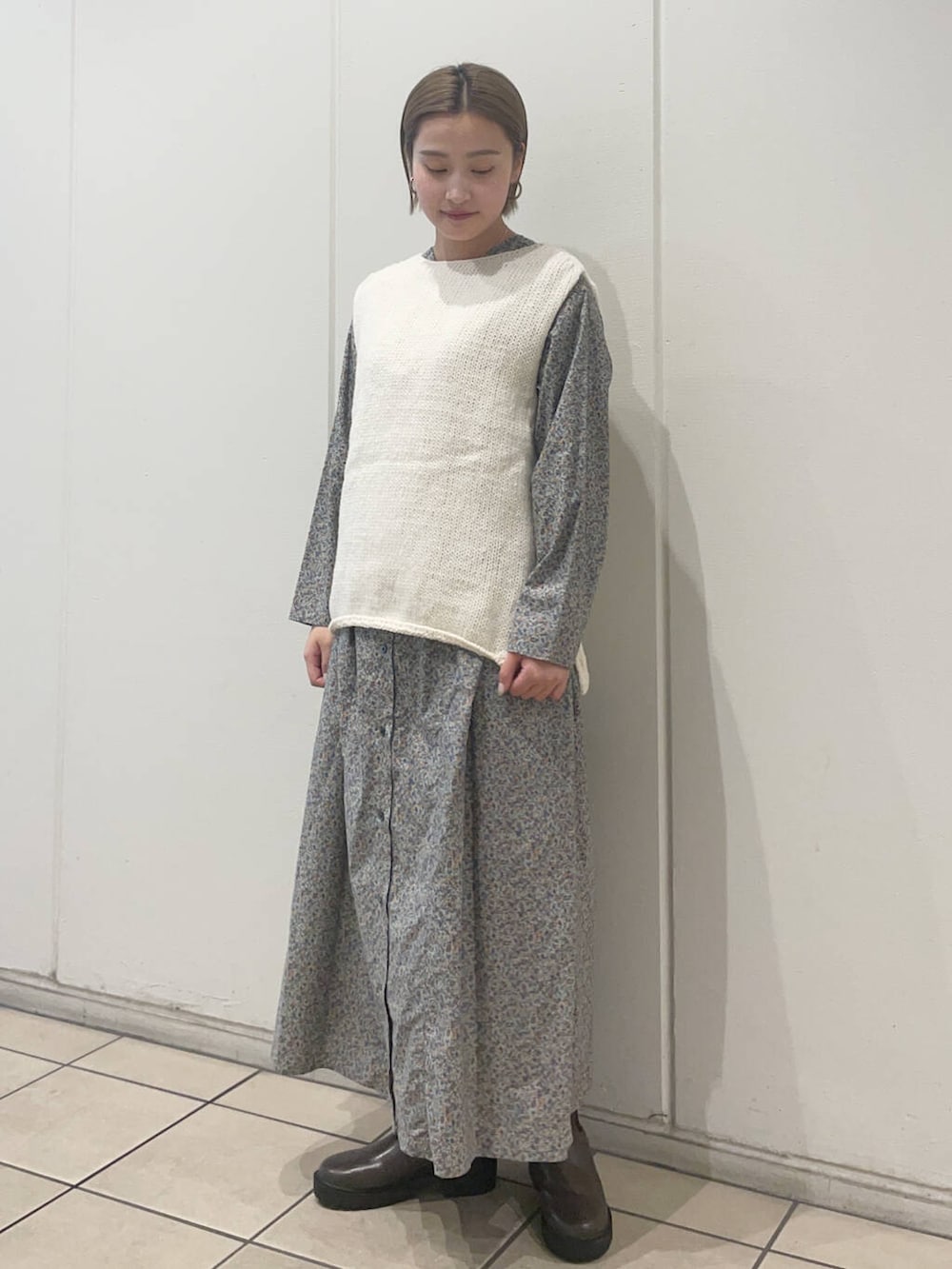 ホワイト系のニット/セーター、ブラウン系のブーツ、グレー系のワンピースを着用したレディースの秋コーディネートの2枚目の写真