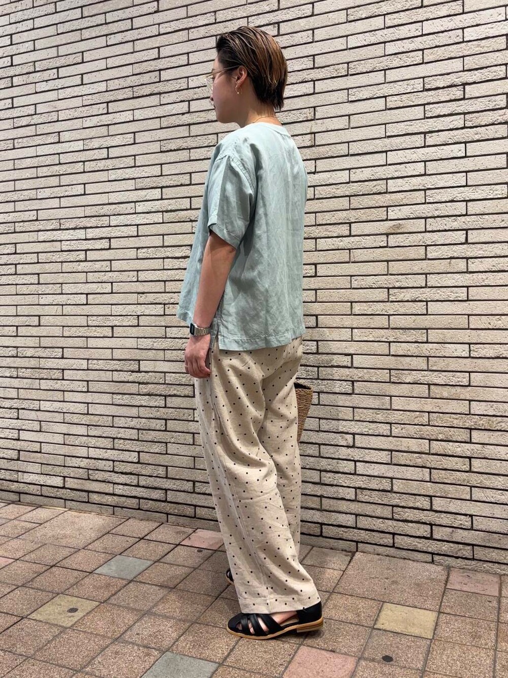 ベージュ系のハンドバッグ、ブラック系のサンダル、グリーン系のTシャツ/カットソーを着用したレディースの夏コーディネートの2枚目の写真