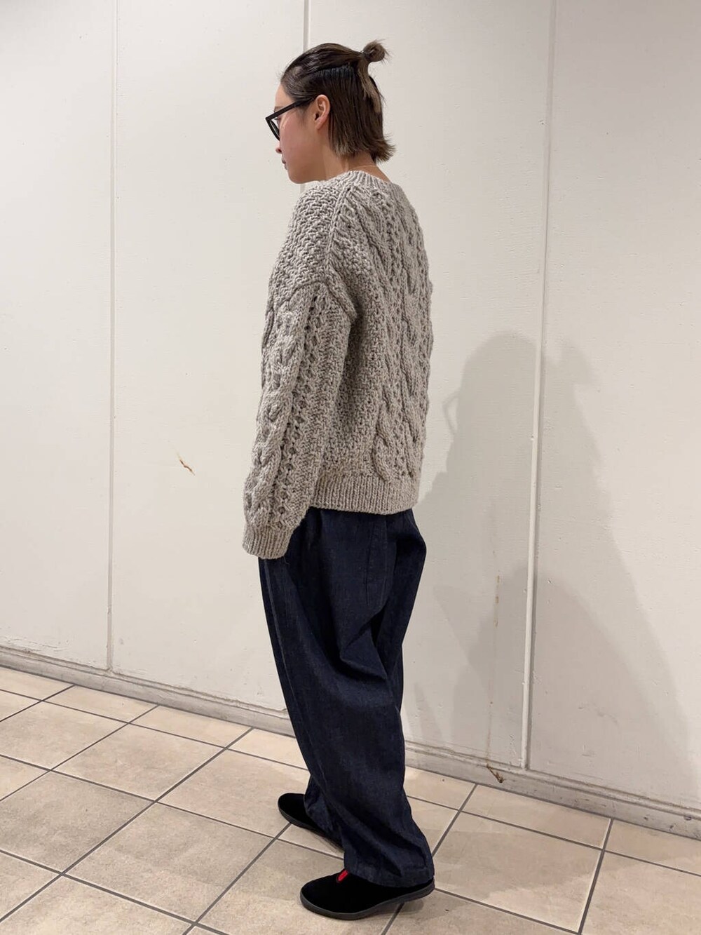 グレー系のニット/セーター、ブルー系のショルダーバッグ、ブルー系のデニムパンツを着用したレディースの冬コーディネートの3枚目の写真