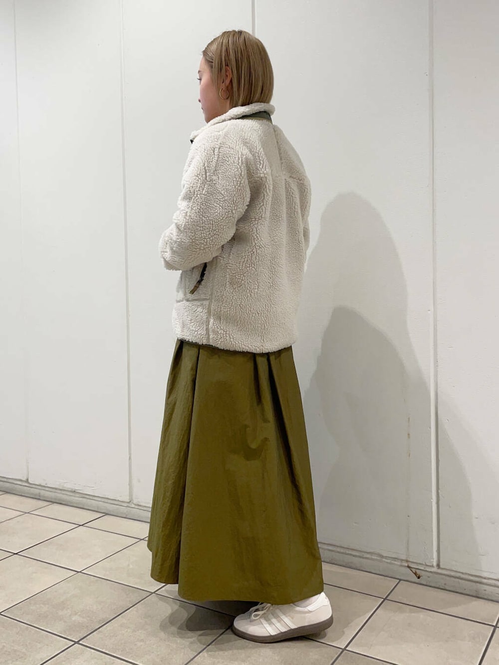 ホワイト系のスニーカー、グリーン系のスカート、グレー系のスウェットを着用したレディースの秋コーディネートの2枚目の写真