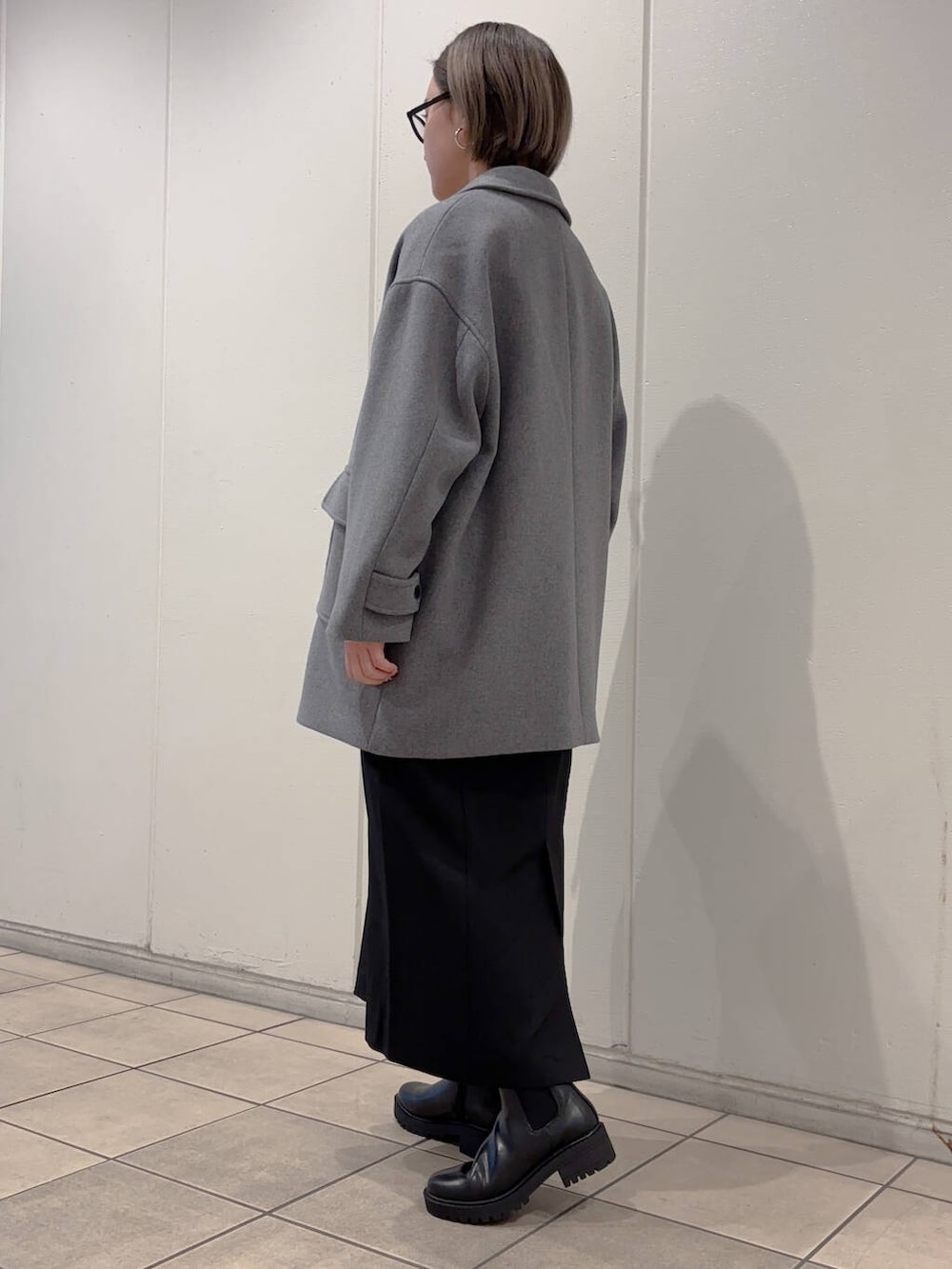 グレー系のその他アウター、ブラック系のブーツ、ホワイト系のニット/セーターを着用したレディースの冬コーディネートの4枚目の写真