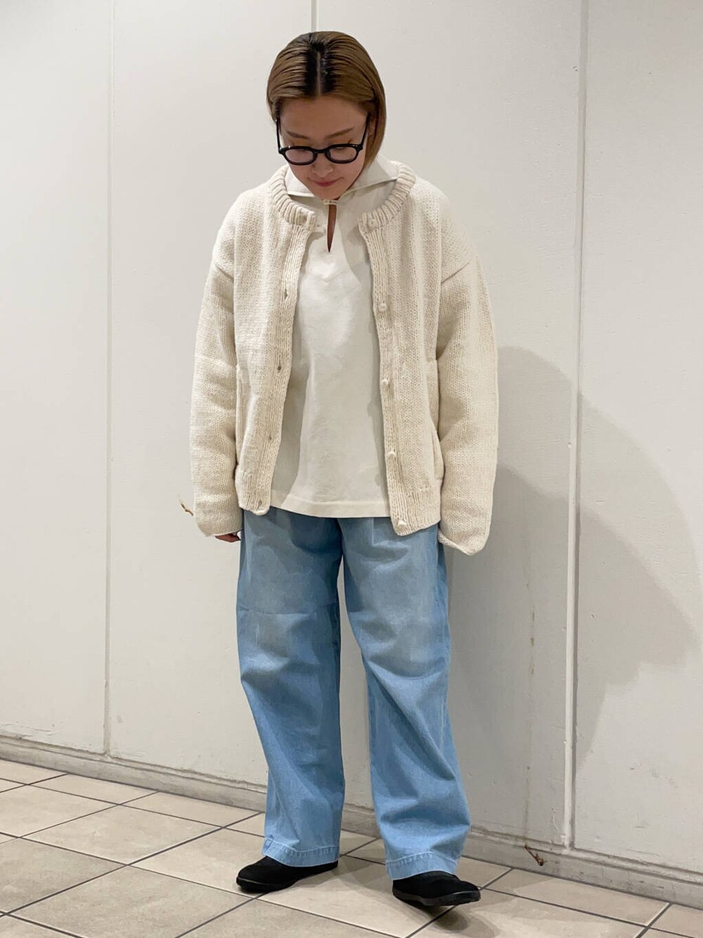 ブラック系のスニーカー、ホワイト系のニット/セーター、ブルー系のデニムパンツを着用したレディースの冬コーディネートの2枚目の写真