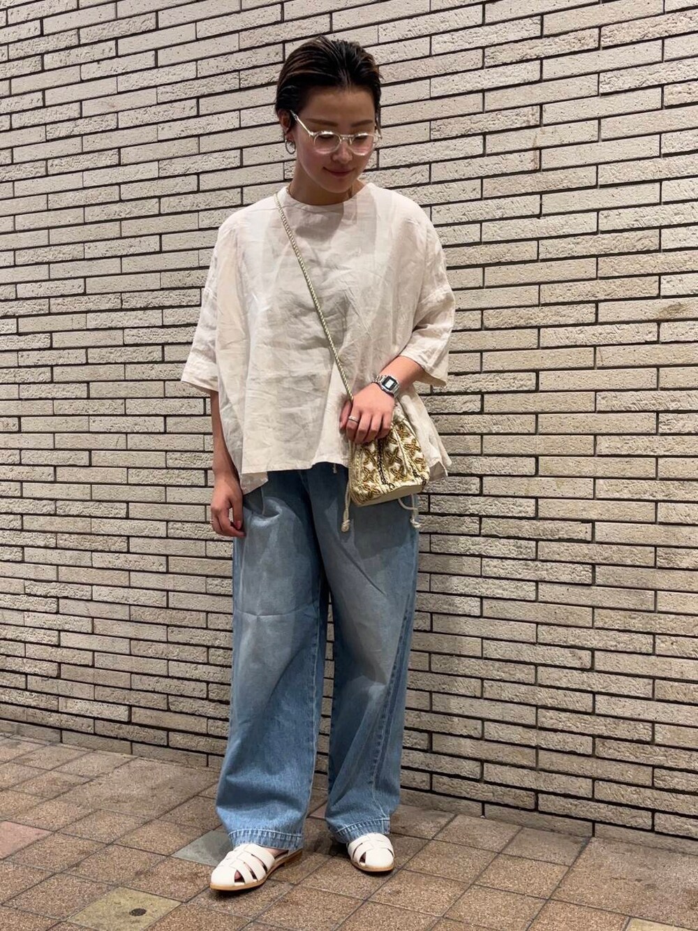 ブルー系のデニムパンツ、ホワイト系のサンダル、ホワイト系のショルダーバッグを着用したレディースの夏コーディネートの2枚目の写真