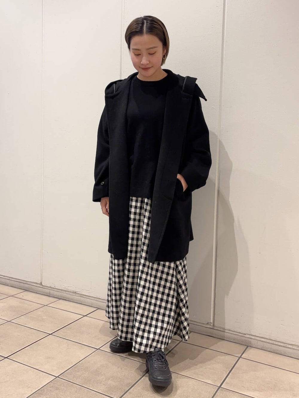 ホワイト系のスカート、ブラック系のその他アウター、ブラック系のニット/セーターを着用したレディースの冬コーディネートの2枚目の写真